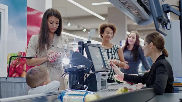 Woman paying with a smart watches in a grocery store