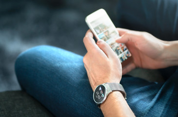 Wireless connection between smart watch and mobile phone. Man using wearable gadget and digital...