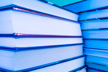 Piles of books in neon blue light. The concept of reading, book publishing, libraries, novelties of literature. Minimalism, place for text.