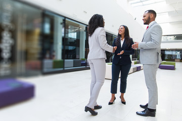 Cheerful business partners happy to see each other. Business man and women standing in office hall, shaking hands with each other, talking and smiling. Successful partnership concept