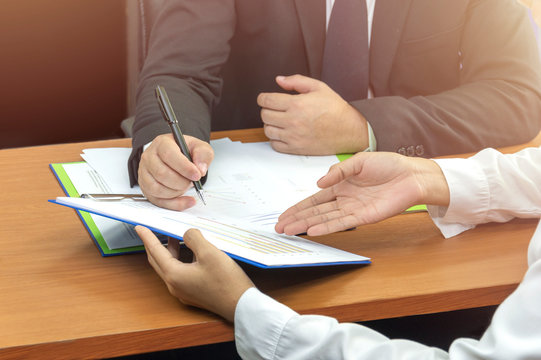 Business man hand signing on document with partner ,Asian women and men are doing business in the office, Business concept and contract signing