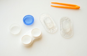 Accessories for use of contact lenses: case, tweezers, blister pack and solution on white background. Safe vision correction. View from above.