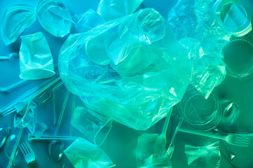 top view of crumpled plastic bags and cups in blue light