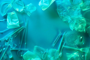 top view of crumpled plastic bags, cups and cardboard rubbish in blue light