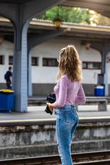 Young girl walking alone on train platform and taking photos on railway station