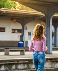 Young girl walking alone on train platform and taking photos on railway station