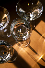 Drink glasses with strong and bright shadows on brown background. Modern art food and water concept 