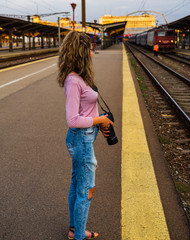 Young girl walking alone on train platform and taking photos on railway station