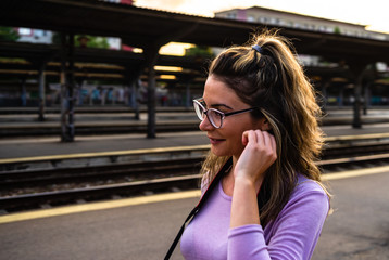 Young girl walking alone on train platform and taking photos on railway station