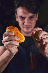 Young chef in kitchen squeeze orange and lime for juice. Food concept.