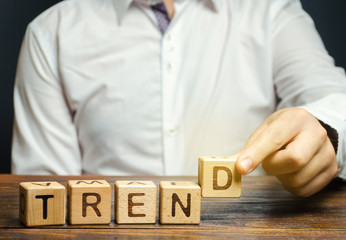 Businessman puts wooden blocks with the word Trend. Popular and relevant topics. New ideological trends. Recent and latest trend. Evaluation methods.