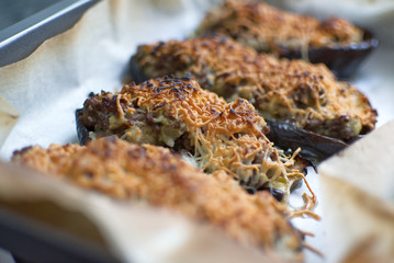 Aubergine stuffed au gratin with meat and cheese from above on a white wooden table of a rustic kitchen.