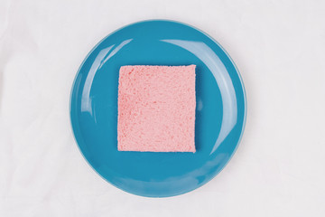 Top view of pink milk flavored sandwich bread on blue sky plate and white cloth background, soft warm tone, Beautiful breakfast concept.
