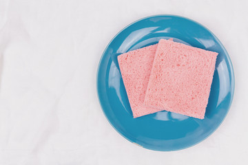 Top view of pink milk flavored sandwich bread on blue sky plate and white cloth background, soft warm tone, Beautiful breakfast concept.