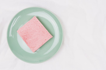 Top view of pink milk flavored sandwich bread on light green plate and white cloth background, soft warm tone, Beautiful breakfast concept.