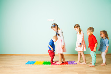 Kids barefoot stand in a row between massage mats
