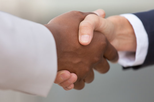 Closeup of diverse business colleagues handshake. Multiethnic business partners shaking hands with each other. Multiethnic partners concept