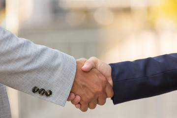 Fototapeta premium Closeup of business partners handshake. Business man and woman shaking hands with each other outside. Closing deal concept