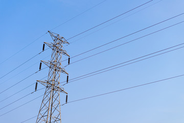 High voltage electricity pylon on blue sky.