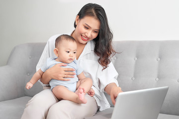 Happy family mother and baby at home using laptop computer