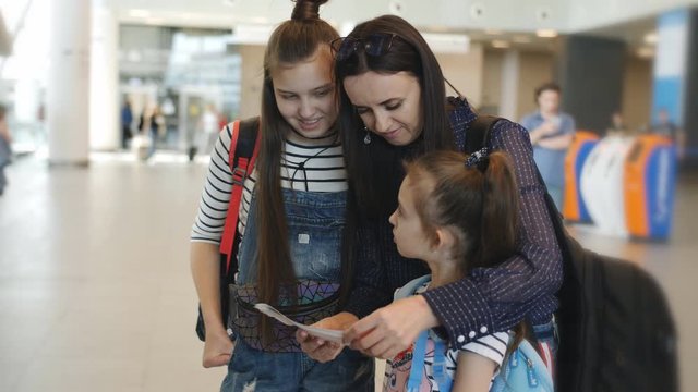Mother with her daughters at the airport checks the tickets for the flight before signing up.