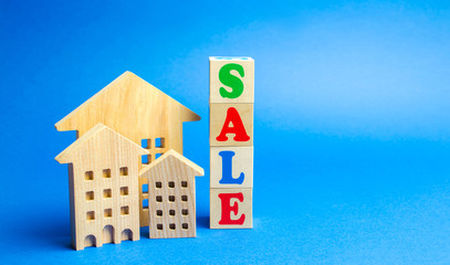 Fototapeta na wymiar Wooden blocks with the word Sale and wooden miniature houses. The concept of the sell of real estate, apartments and residential premises. Rent and mortgage. Market analysis