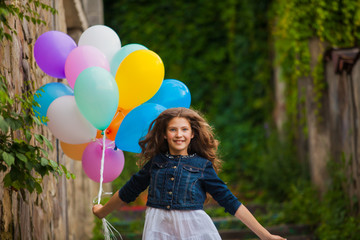 Girl is running with colorful balloons outdoors