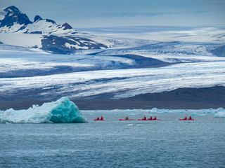 A group of friends in red kayaks near the Jökulsárlón glacier lagoon.