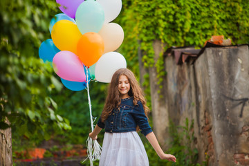 Girl is running with colorful balloons outdoors
