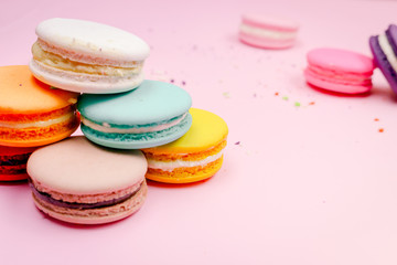 Obraz na płótnie Canvas Colorful french macarons (macaroons) cake, delicious sweet dessert on a pink background with copyspace, food background concept.