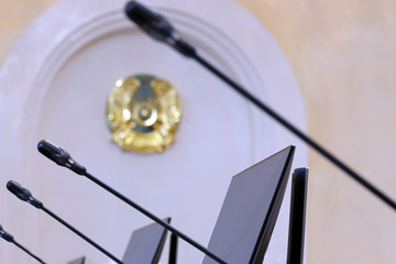 Blurred background for official news of Kazakhstan. Microphones, monitors and emblem.