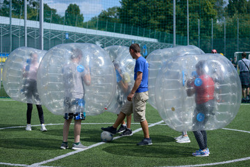 Man keeping ball in the center of a football field by his leg, before beginning of bubble football match
