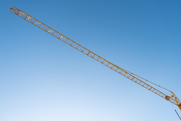 Construction crane from below, against a blue sky on a sunny day