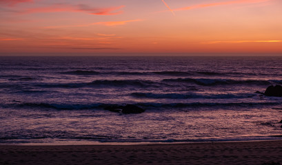 Fototapeta premium Beautiful dusk over ocean with dark purple waves and orange red sky