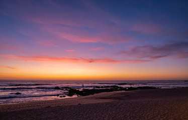 Fototapeta na wymiar Beautiful dusk over beach in summer with vivid blue orange gradient sky and reflections on ocean surface