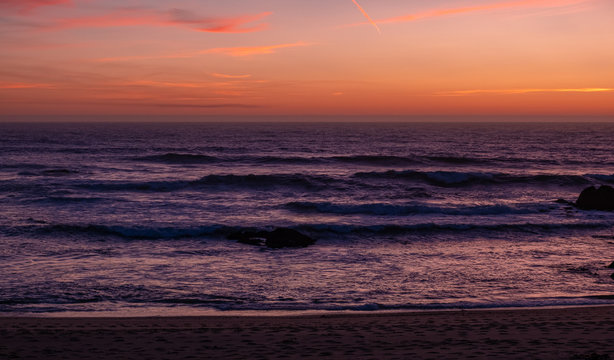 Beautiful dusk over ocean with dark purple waves and orange red sky