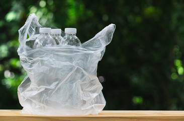 Plastic bottle in plastic bag on wooden in nature background. global warming concept.