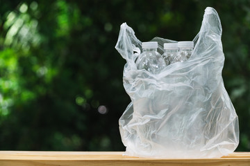 Plastic bottle in plastic bag on wooden in nature background. global warming concept.