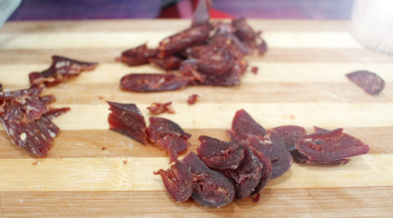 Jerky, biltong, jerk, jerked meat on a wooden board. Dry meat pattern.