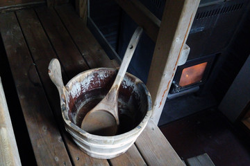 Inside of old Finnish sauna. Sauna bucket with water and scoop. Flames in sauna stove.