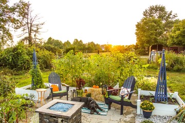 Outdoor patio and raised garden beds at sunset, decorated for Autumn with pumpkins, plants, hay...