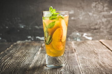 Tasty peach tea in glass on the rustic background. Selective focus. Shallow depth of field.