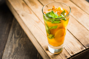 Tasty peach tea in glass on the rustic background. Selective focus. Shallow depth of field.