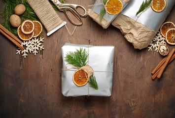 Packaging christmas present handmade gift boxes decorated with silver paper with dried orange slices