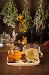 Cup of hot tea with honey, spices and drying medical herbs for use in alternative medicine