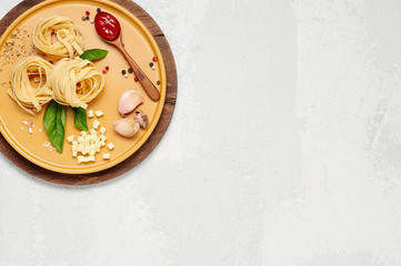 Obraz na płótnie Canvas Ingredient for simple italian dinner on yellow plate. Fettuccine, fresh basil, tomato souce and mozzarella cheese