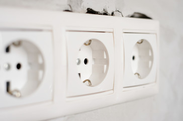 Electric EU socket outlet on gray concrete wall background. Repair in an apartment or in office, replacement of electrical wiring. Close up view.
