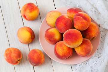 Fresh organic peaches in a plate on a white wooden table