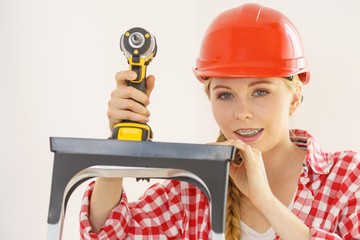Woman wearing helmet using drill
