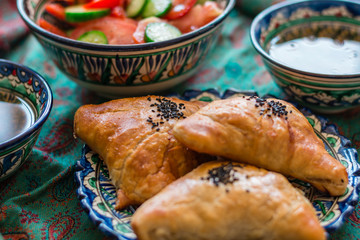 Uzbek Samsa or Sambousak in national plate. Samsa or Sambousak an oriental meal to be stuffed with minced meat, cheese or vegetables. The national dish of Uzbekistan and Central Asia.